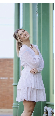 Smiling young woman standing outdoors on a bright day.