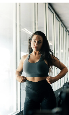 Woman in athletic wear standing confidently in a bright gym.
